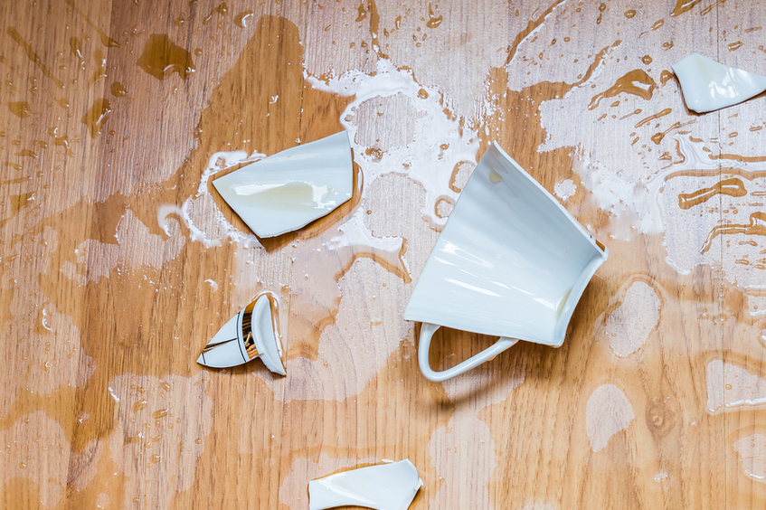 Broken cup on the floor with liquid.